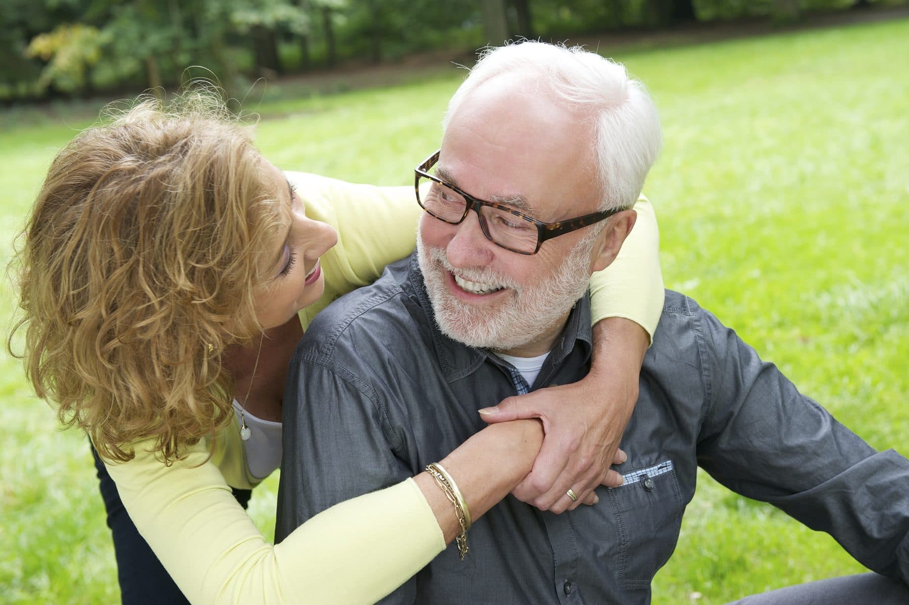 An older couple embracing and laughing together in a park