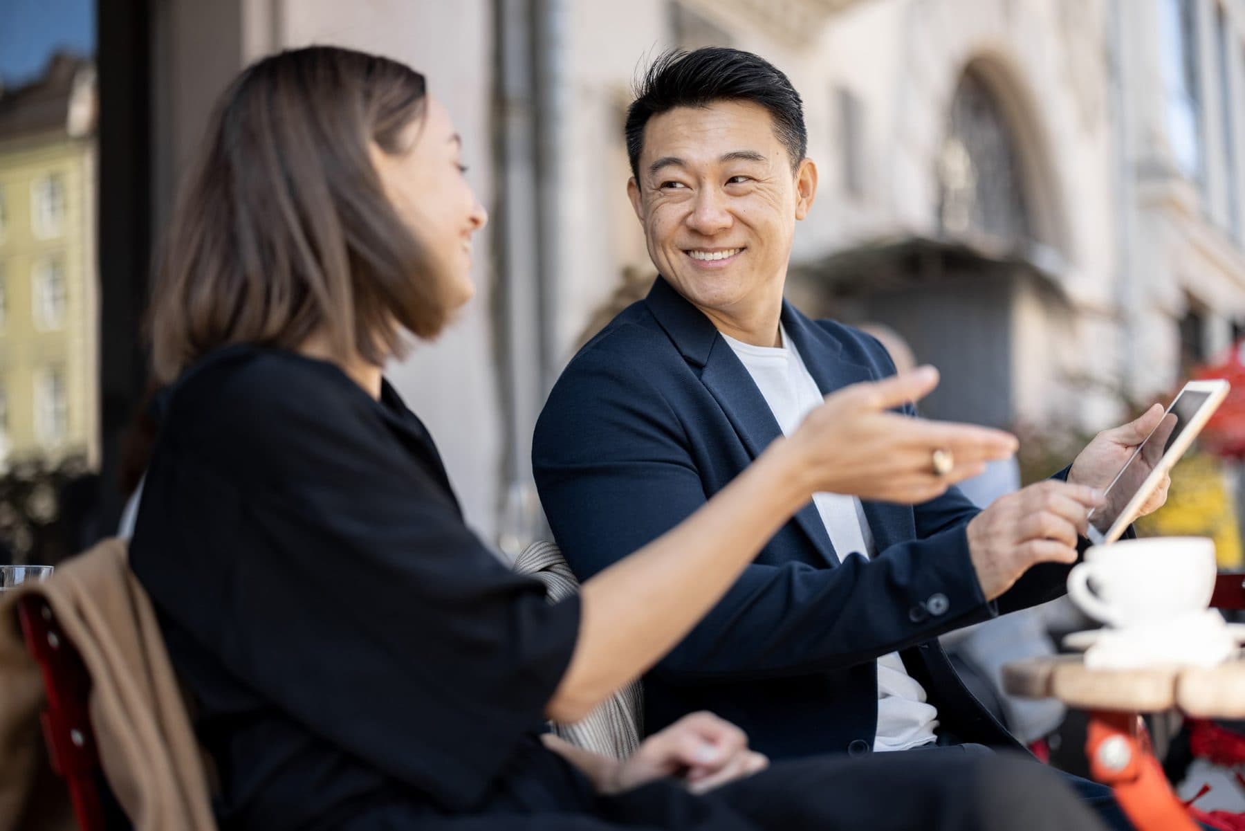A woman and man chatting easily at an outdoor café table