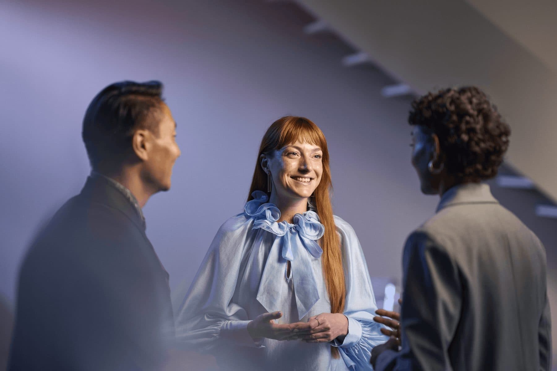 A smiling woman chatting with two friends at a social event