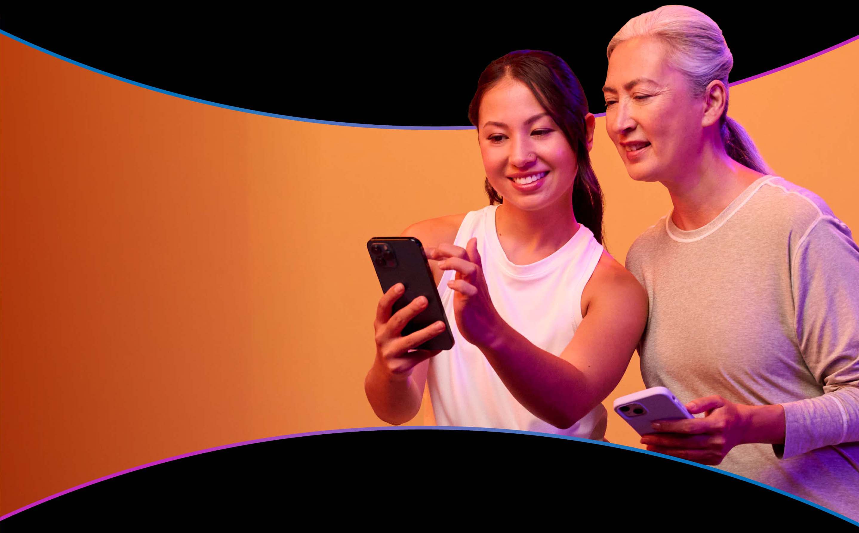 An older woman and her daughter smiling together over a phone, sharing every word